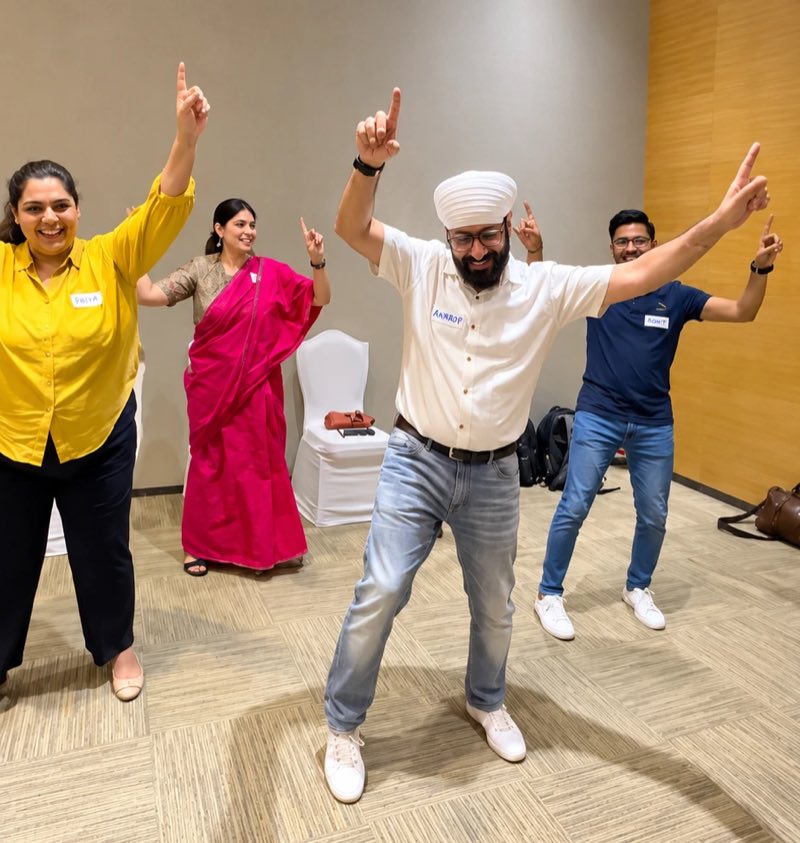Four managers mid-movement during an energiser, arms in the air