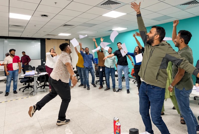 A full room of managers on their feet, paper in the air, cheering