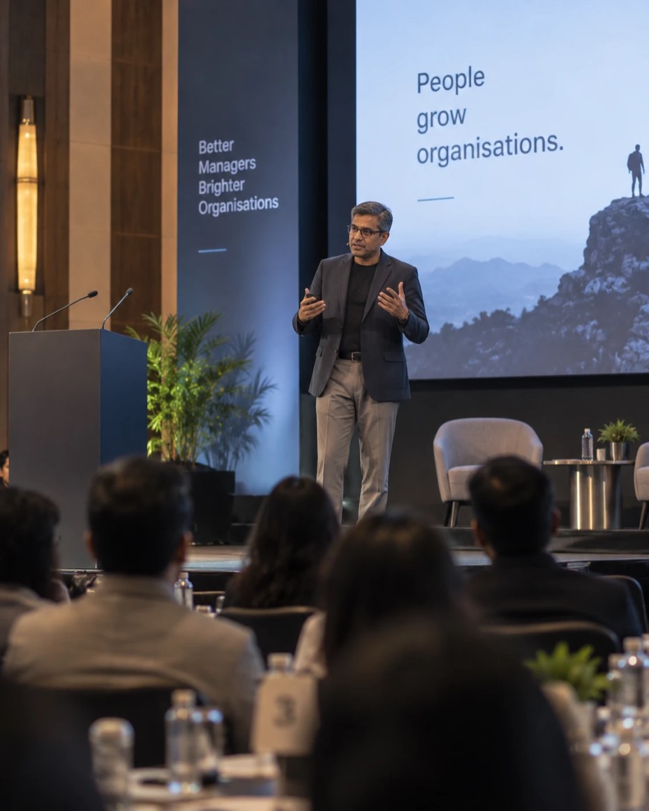 A senior leader speaking on stage to an audience at a leadership event