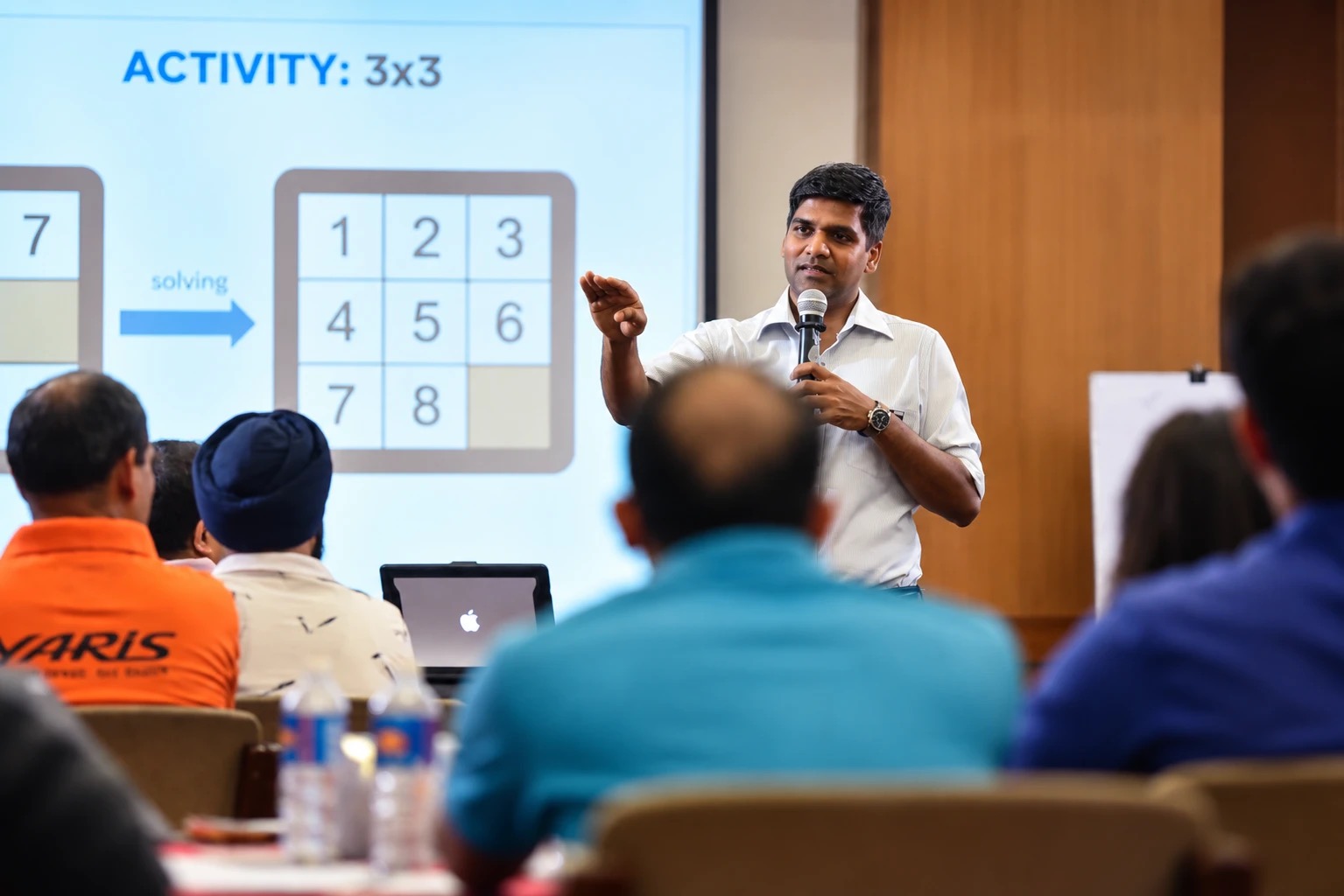 A Change+ facilitator running the 3x3 activity with a room of managers, the exercise on screen behind him