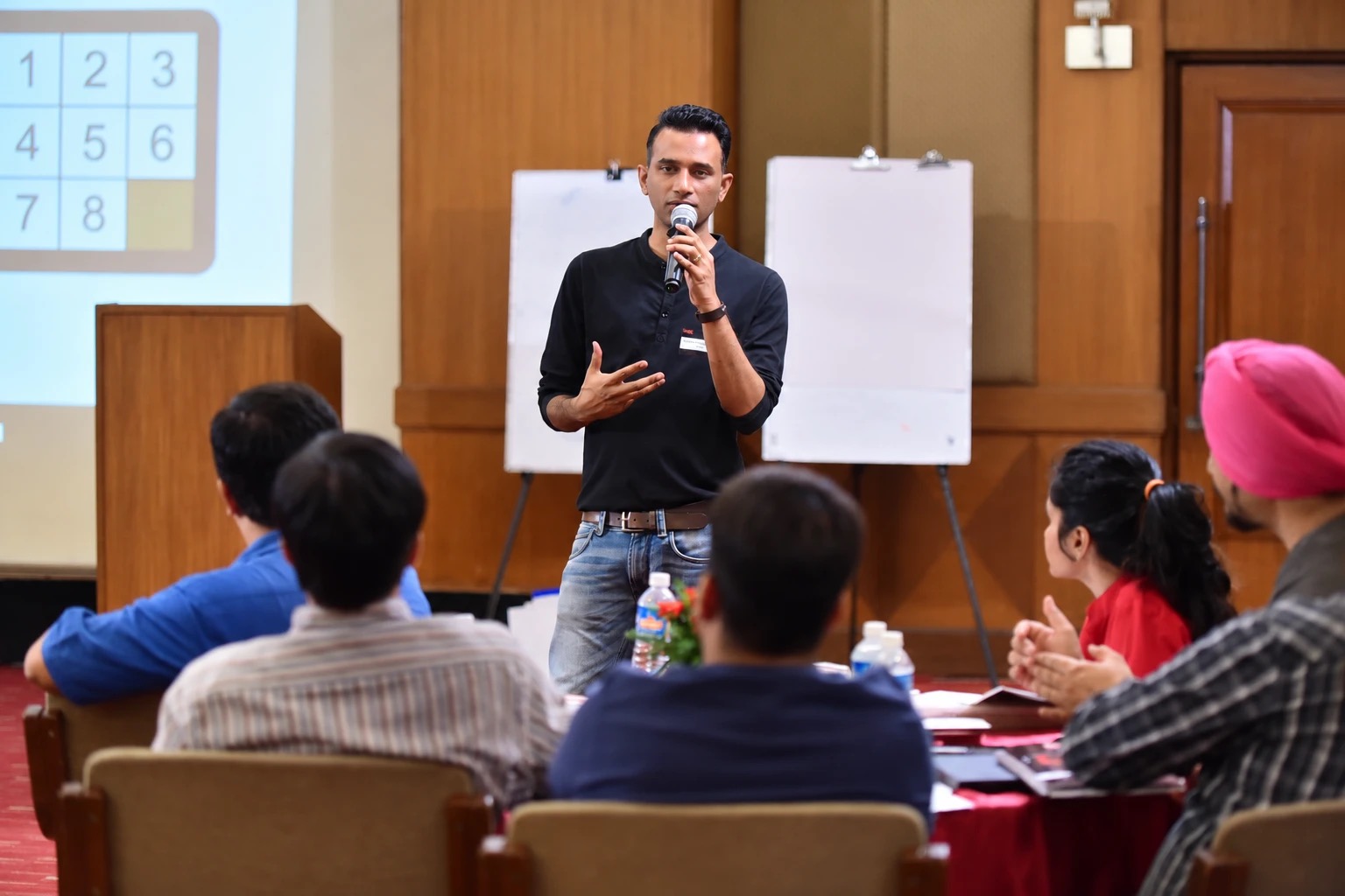 A Change+ facilitator mid-session with a room of managers, flipcharts behind him